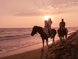 The family spends time with their children while riding horses together on a sandy beach. Selective focus photo