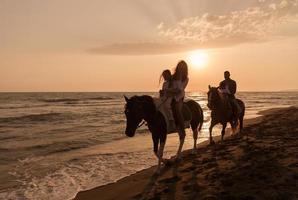 la familia pasa tiempo con sus hijos mientras montan a caballo juntos en una playa de arena. enfoque selectivo foto