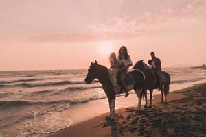 la familia pasa tiempo con sus hijos mientras montan a caballo juntos en una playa de arena. enfoque selectivo foto