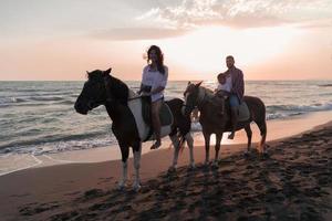 The family spends time with their children while riding horses together on a sandy beach. Selective focus photo