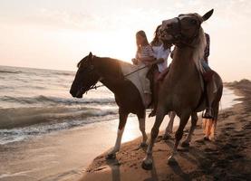 la familia pasa tiempo con sus hijos mientras montan a caballo juntos en una playa de arena. enfoque selectivo foto