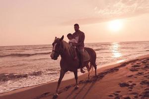 la familia pasa tiempo con sus hijos mientras montan a caballo juntos en una hermosa playa de arena en sunet. foto