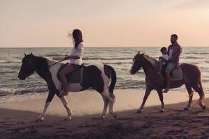 la familia pasa tiempo con sus hijos mientras montan a caballo juntos en una playa de arena. enfoque selectivo foto