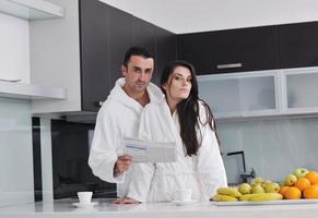 Happy couple reading the newspaper in the kitchen at breakfast photo