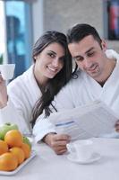 Happy couple reading the newspaper in the kitchen at breakfast photo