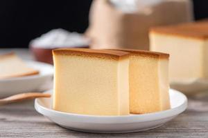 Castella - Delicious Japanese sliced sponge cake food on white plate over rustic wooden table, close up, healthy eating, copy space design. photo