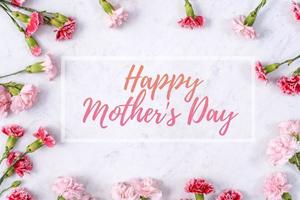 Happy Mother's Day background design concept with greeting words, beautiful pink, red carnation flower bouquet on marble table, top view, flat lay, copy space. photo