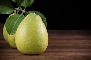 Fresh pomelo, pummelo, grapefruit, shaddock on wooden table over black background, close up, copy space. Fruit for Mid-autumn festival. photo