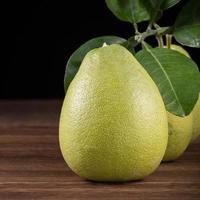 Fresh pomelo, pummelo, grapefruit, shaddock on wooden table over black background, close up, copy space. Fruit for Mid-autumn festival. photo