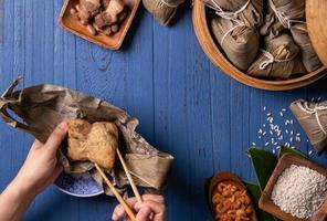 zongzi - bola de arroz con concepto del festival del bote del dragón, comida tradicional china sobre fondo de madera azul para el festival duanwu, vista superior, concepto de diseño plano. foto