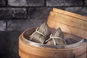 Rice dumpling, zongzi - Chinese rice dumpling zongzi on black brick background slate table, concept of Dragon Boat Festival traditional food, close up. photo