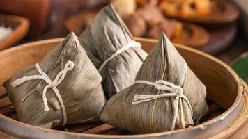 Rice dumpling, zongzi - Chinese rice dumpling zongzi in a steamer on wooden table with red brick, window background at home for Dragon Boat Festival concept, close up. photo