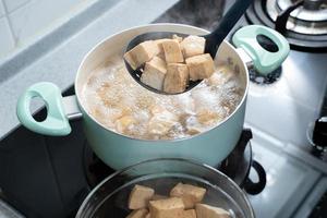 cocinar tofu seco en cubitos en una estufa de gas en la cocina casera, estilo de vida, primer plano. foto