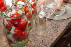 The process of preserving tomatoes for the winter. Ripe red juicy tomatoes in glass jars. photo