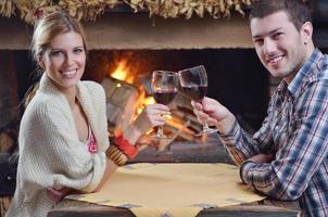 joven pareja romántica sentada y relajándose frente a la chimenea en casa foto