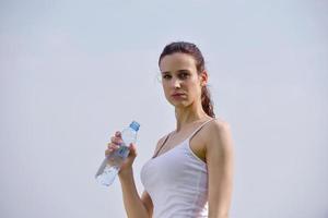 Young beautiful woman drinking water after fitness exercise photo