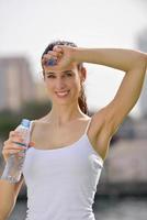 Young beautiful woman drinking water after fitness exercise photo
