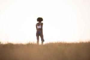 young black girl dances outdoors in a meadow photo