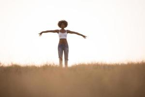 young black girl dances outdoors in a meadow photo
