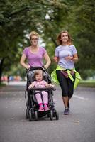 women with baby stroller jogging together photo