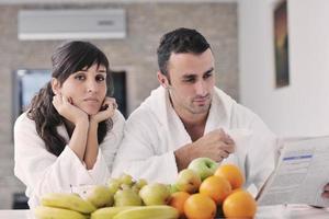 Happy couple reading the newspaper in the kitchen at breakfast photo