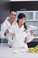 pareja feliz leyendo el periódico en la cocina durante el desayuno foto