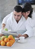 pareja feliz leyendo el periódico en la cocina durante el desayuno foto