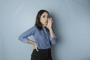 Young beautiful woman wearing a blue shirt shouting and screaming loud to the side with a hand on her mouth. communication concept. photo