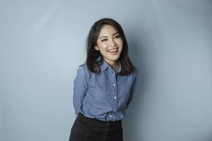 A portrait of a happy Asian woman is smiling and wearing a blue shirt isolated by a blue background photo