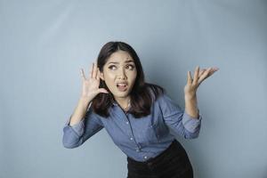 Amazed curious bride young woman wearing a blue shirt trying to hear you overhear listening intently isolated on blue turquoise background studio portrait. photo