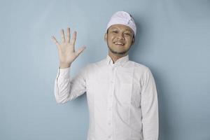 Excited Balinese man wearing udeng or traditional headband and white shirt giving number 12345 by hand gesture photo