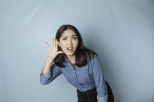 Amazed curious bride young woman wearing a blue shirt trying to hear you overhear listening intently isolated on blue turquoise background studio portrait. photo