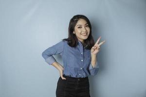 mujer asiática emocionada con una camisa azul dando el número 12345 con un gesto manual foto