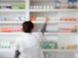 blur pharmacist taking medicine from shelf in pharmacy photo