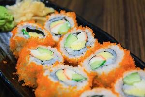 Sushi roll, row of California maki roll sushi with caviar on black plate photo