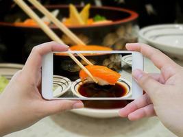 Taking photo of Salmon sushi in chopsticks