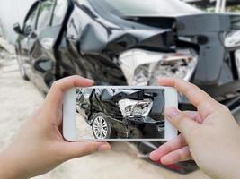 accidente automovilístico dañado con la mano usando un teléfono inteligente tomando una foto