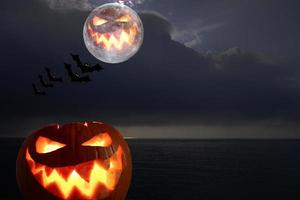 el fondo oscuro de la noche en el mar con calabaza y luna llena halloween. fondo de halloween foto