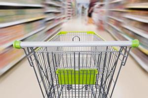 Empty shopping cart with abstract blur supermarket discount store aisle and product shelves interior defocused background photo