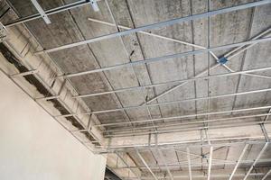 Install metal frame for plaster board ceiling at house under construction photo