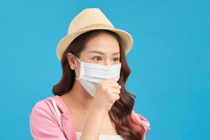 Dissatisfied woman in hat protects face with mask, thinks abot risk of epidemic disease, has virus infection photo