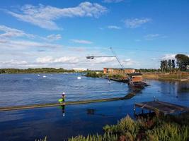 Beautiful Aerial Drone's Camera  Footage of Willen Lake and Park which is located at Milton Keynes, England. People are Enjoying at Lake on a Hot Sunny Day of Summer photo