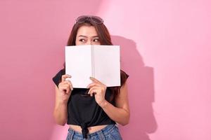 Image of beautiful young pretty woman posing isolated over pink background wall holding book reading. photo