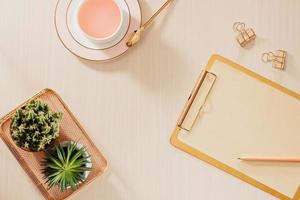 Women's home office workspace with clipboard, macaroons, pen, coffee mug on pastel background. Flat lay, top view lifestyle concept. photo