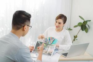 Real-estate agent showing house plans for client at office. photo