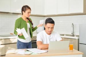 Upset young couple with financial bills having conflict in home interior photo