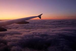 Beautiful view over the clouds from a plane window during sunset photo