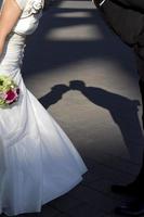 Shadow of newlywed couple leaning forward and kissing photo