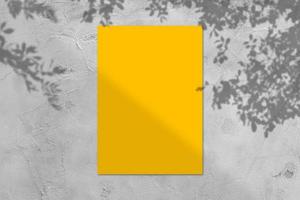 Empty yellow square poster mockup with light shadow on gray concrete wall background. photo
