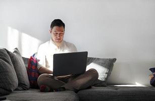 hombre trabajando desde casa con una laptop en la sala de estar foto